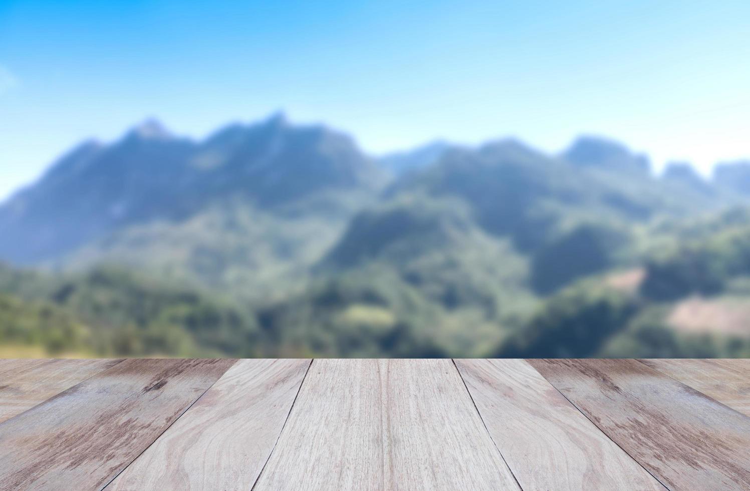 leerer oberer Holztisch und Blick auf den verschwommenen Hintergrund der Berge foto