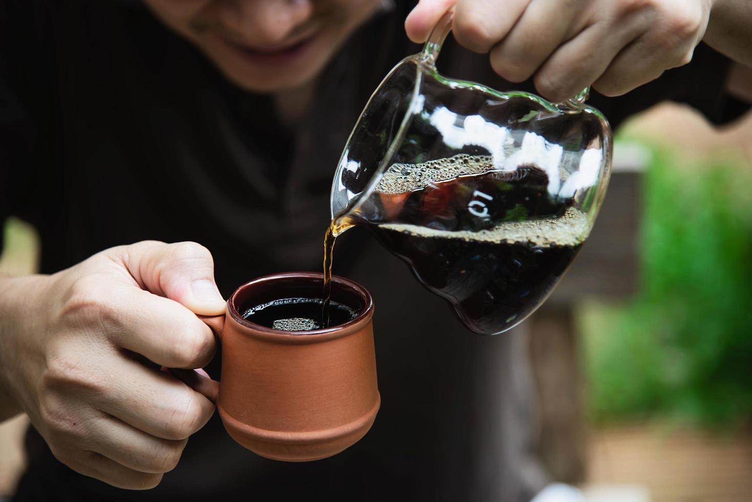 Mann, der frischen Kaffee im Vintage-Café mit grünem Naturhintergrund macht - Menschen mit frischem Kaffee im Naturkonzept foto