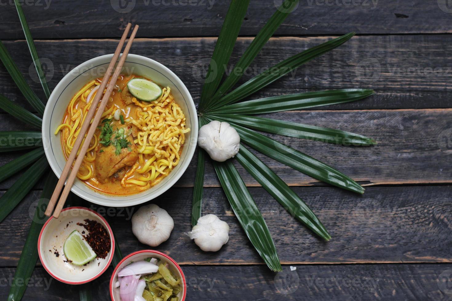 khao soi rezept, khao soi, khao soi kai, thai-nudeln khao soi, hähnchencurry mit gewürzen, serviert auf holztisch foto