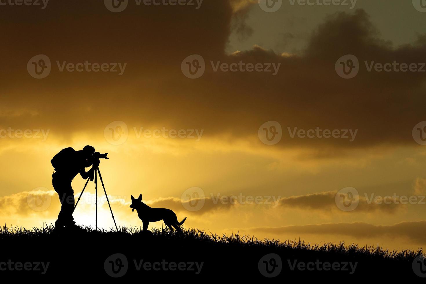 Die Silhouette eines professionellen Fotografen konzentriert sich auf das Fotografieren auf einer wunderschönen Wiese. foto