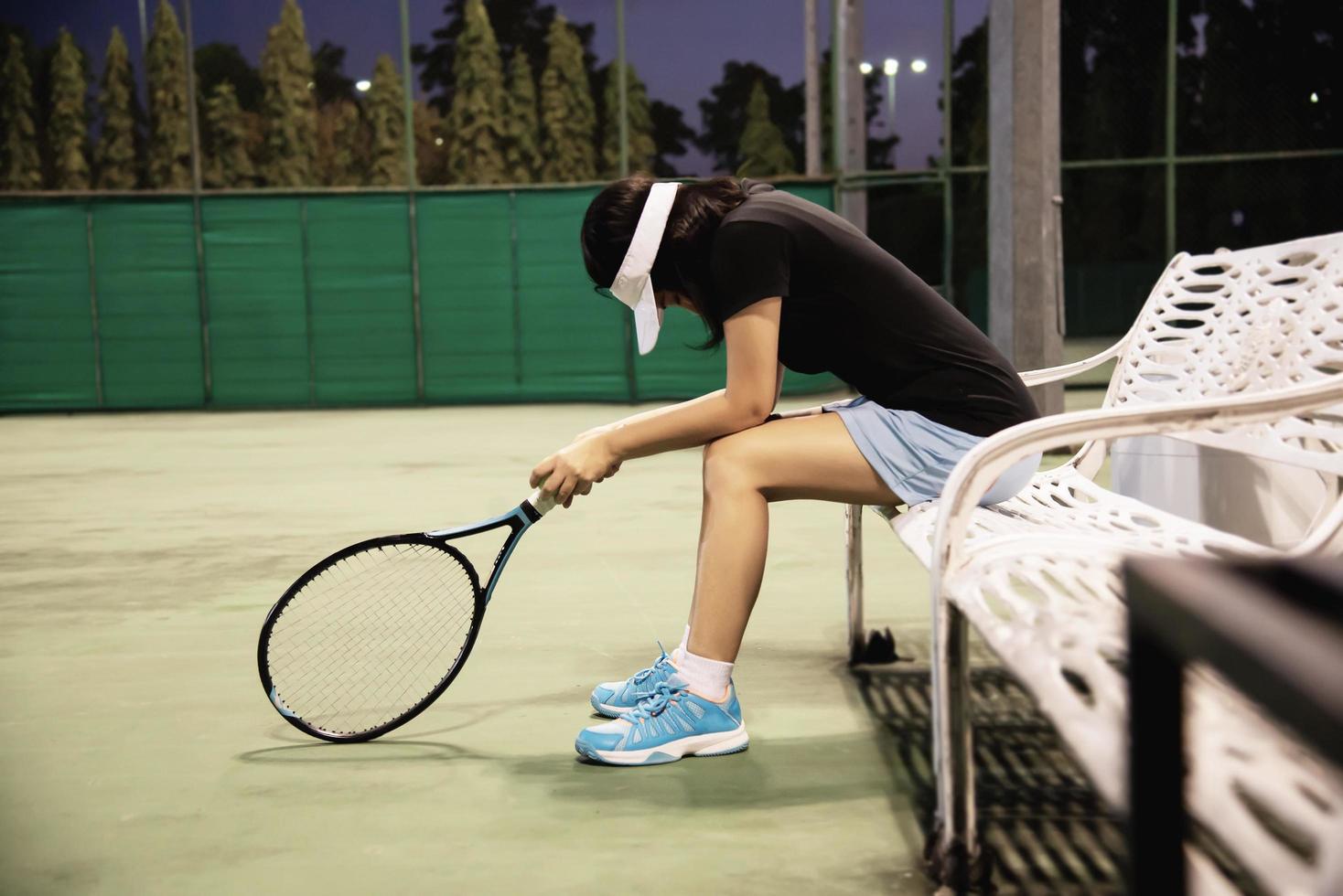 traurige Tennisspielerin, die auf dem Platz sitzt, nachdem sie ein Match verloren hat - Menschen im Sport-Tennis-Spielkonzept foto