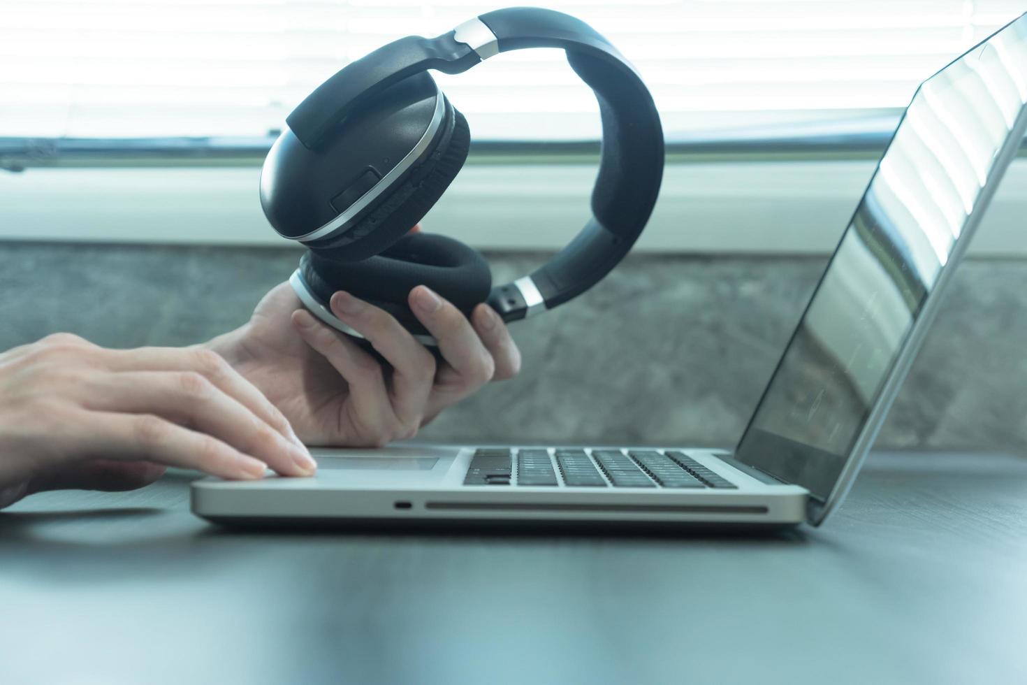 nahaufnahme männlicher hände, die kopfhörer halten und laptop auf dem tisch verwenden foto