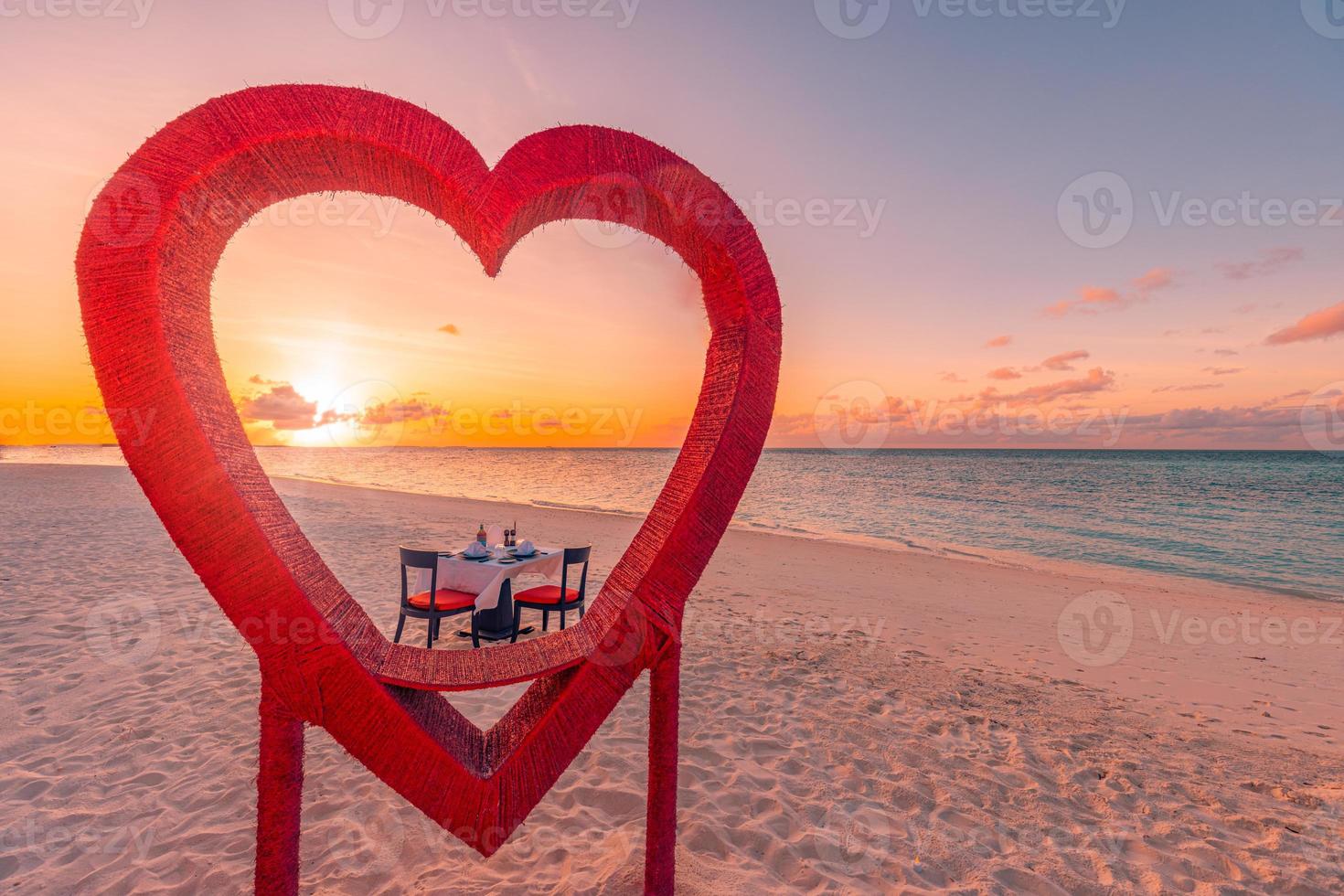 Abendessen für Flitterwochenpaare bei privatem, luxuriösem, romantischem Abendessen am tropischen Strand auf den Malediven. Meerblick, erstaunliche Inselküste mit roten herzförmigen Tischstühlen. romantisches Liebesziel foto
