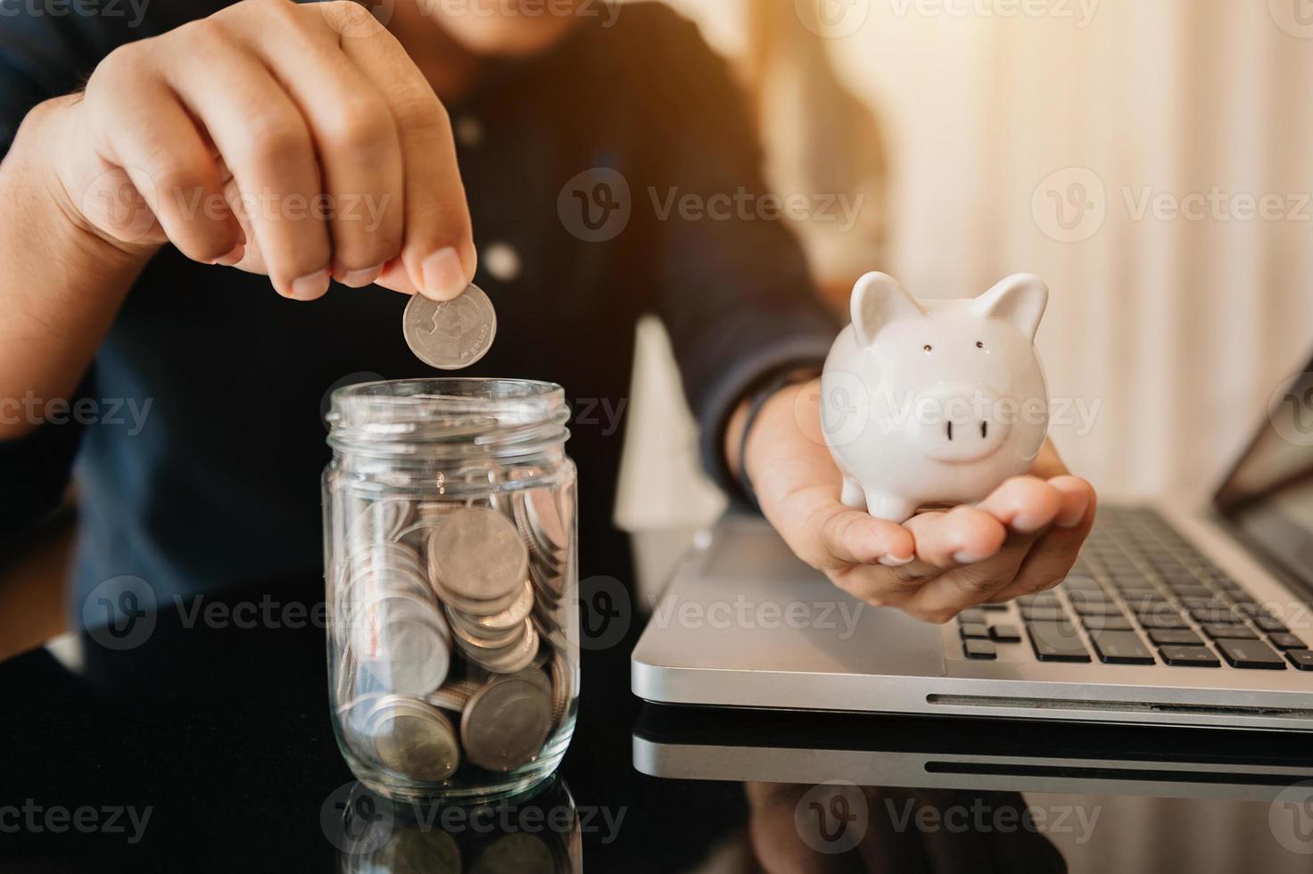 geschäftsfrau, die münzen hält, die glas mit smartphone und taschenrechner einlegen, um das konzept zu berechnen, das geld in sparschwein spart foto