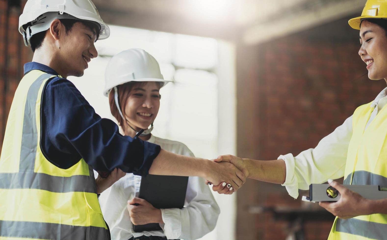 Handschlag eines männlichen Bauingenieurs oder Architekten mit dem Auftragnehmer, nachdem er über die Gestaltung von Baustilen gesprochen und den Fortschritt des Wohnungsbauprojekts auf Baustellen überprüft hat. foto