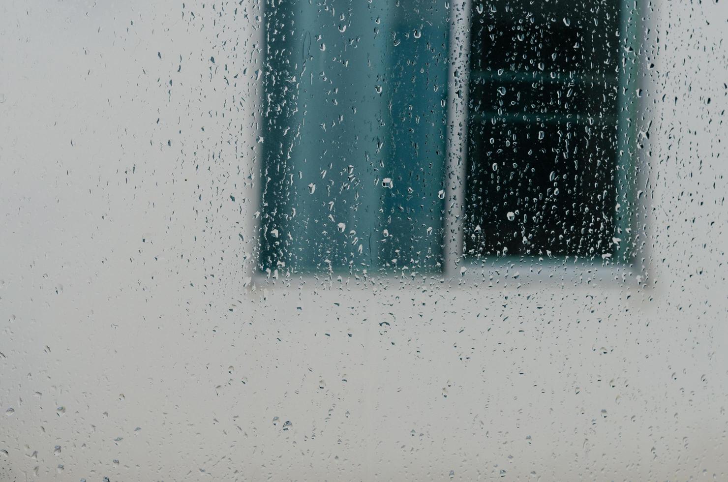 Regentropfen auf dem Fenster des Haushintergrunds foto