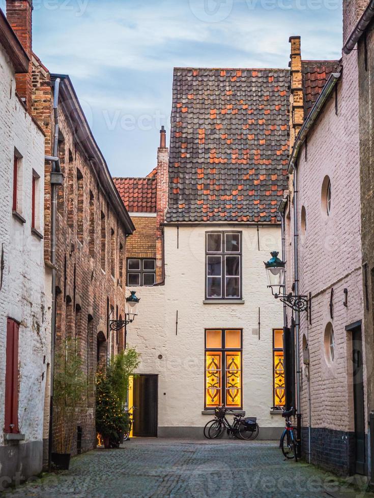 die frontansicht eines schönen hauses mit seinem niedlichen dach aus roten und schwarzen ziegeln in einer schmalen straße in brügge, belgien. foto