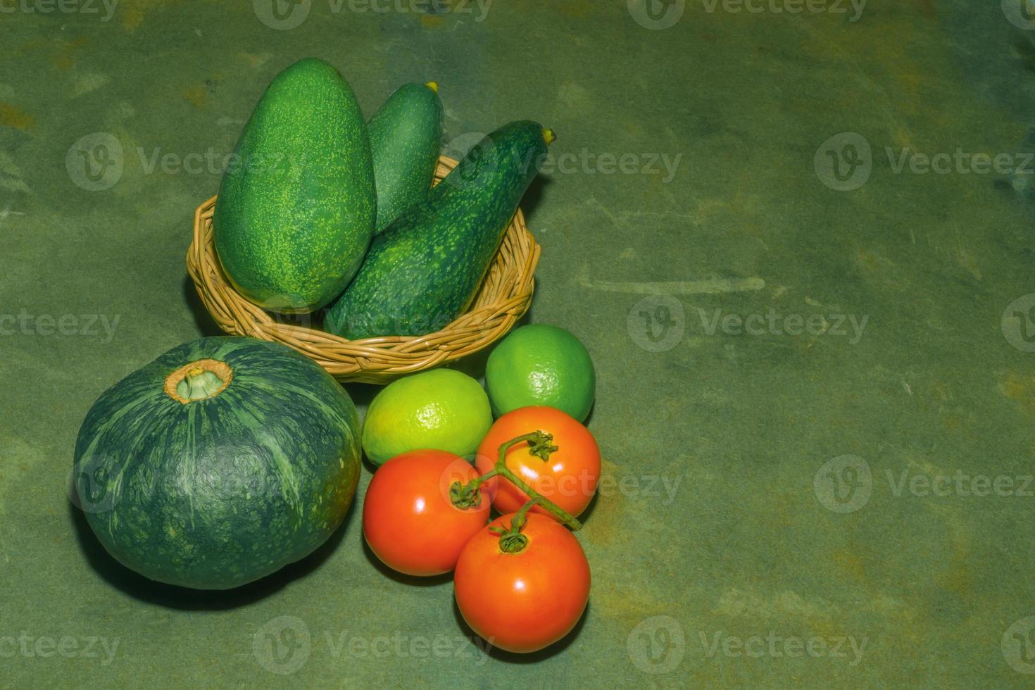 Kombination aus Obst und Gemüse Avocado Kürbis grüne Zitrone und Tomate auf Holztisch hautnah. foto