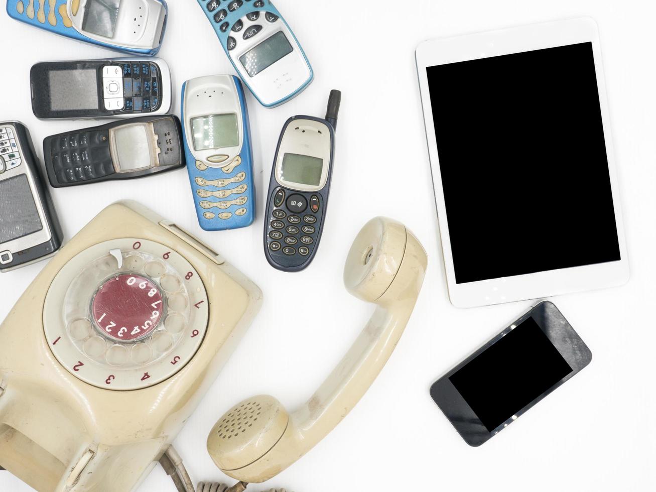 Tablet mit Smartphone und alten Telefonen auf weißem Hintergrund foto
