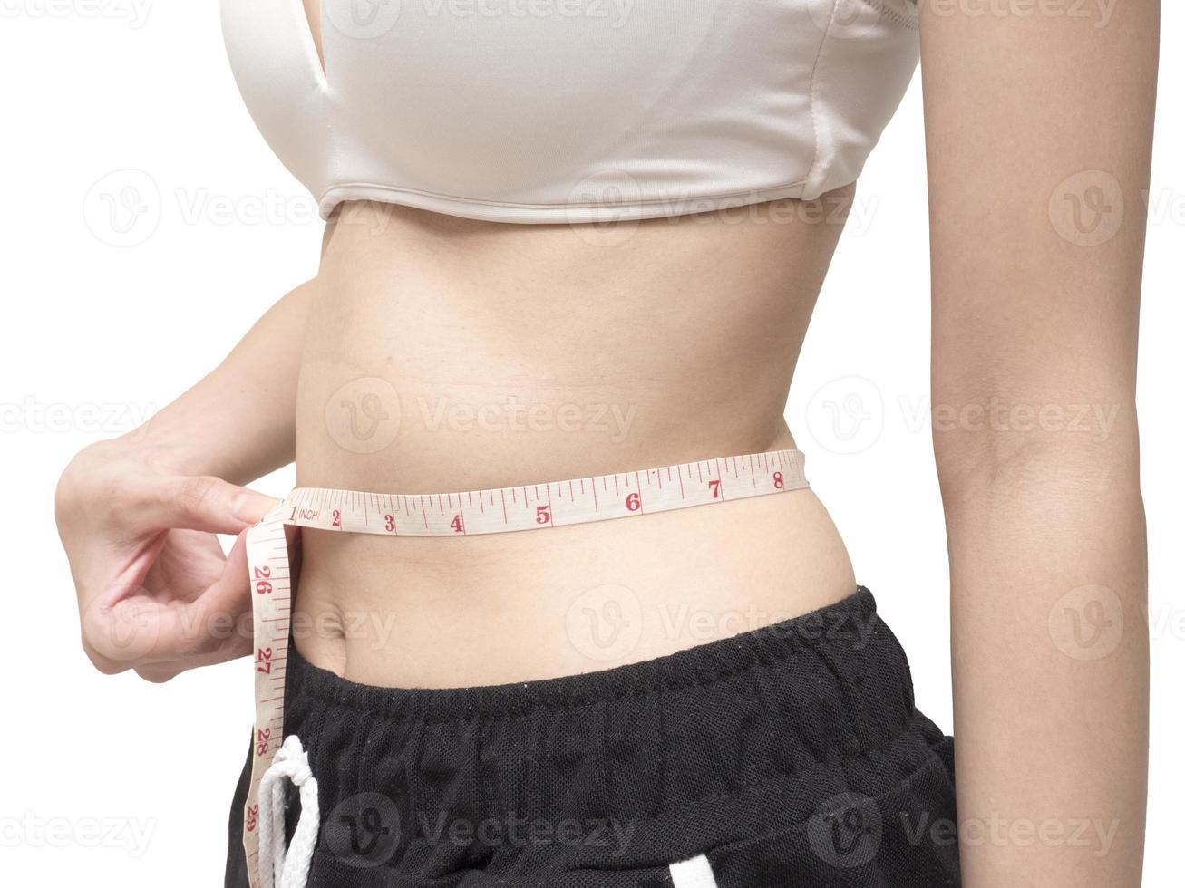Nahaufnahme des weiblichen Körpers, der ihre Taille auf weißem Hintergrund, Ernährung und gesundem Lebensstil misst foto