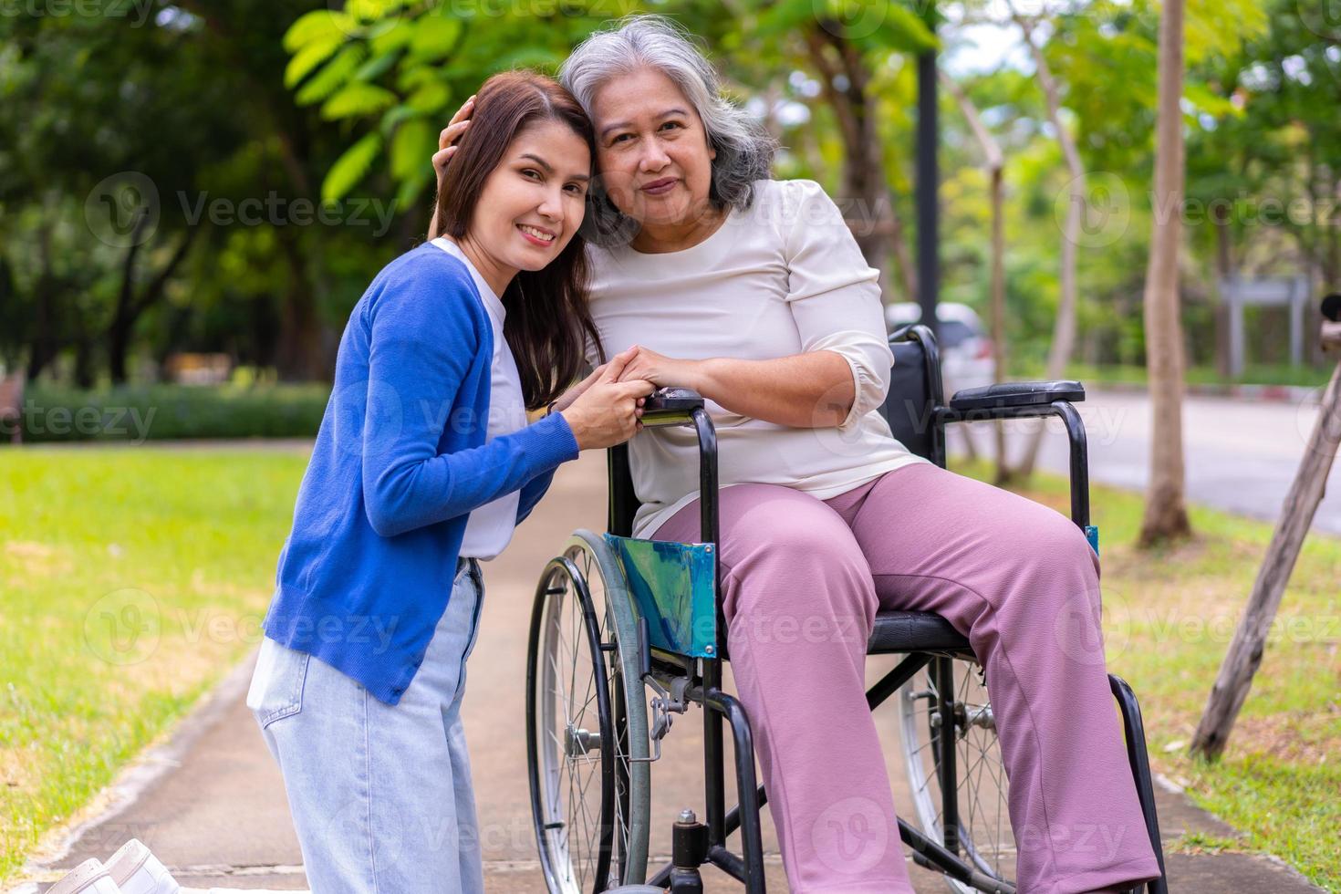 asiatische Pflegekraft oder Krankenschwester, die sich um den Patienten im Rollstuhl kümmert. Konzept des glücklichen Ruhestands mit Betreuung durch eine Pflegekraft und Spar- und Seniorenkrankenversicherung, eine glückliche Familie foto