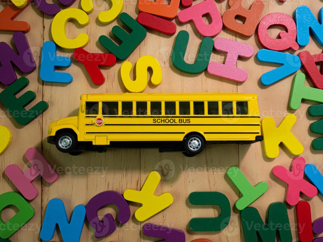 das mehrfarbige holzalphabet und der schulbus auf dem tisch für bildung oder kinderkonzept foto