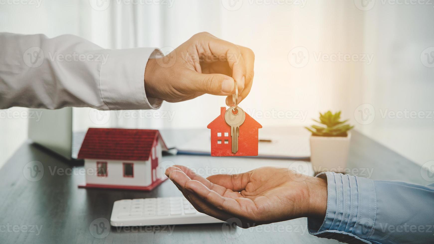 immobilienmakler, der seinem kunden nach unterzeichnung des vertrags den hausschlüssel hält, konzept für geschäftsdarlehen, investitionshypotheken, immobilien, umzug oder miete. foto