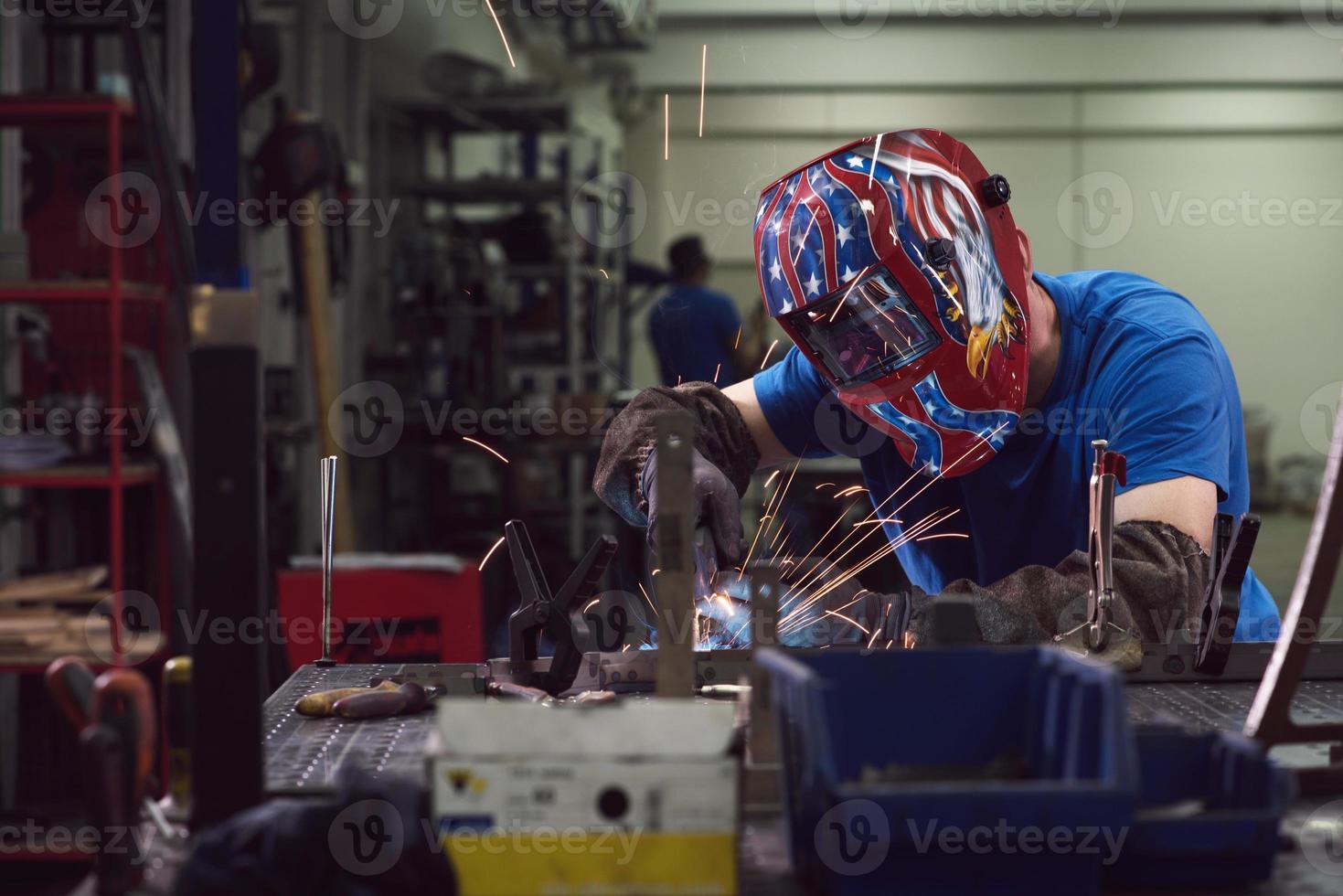 professioneller Schweißer aus der Schwerindustrie, der in der Fabrik arbeitet, einen Helm trägt und mit dem Schweißen beginnt. selektiver Fokus foto