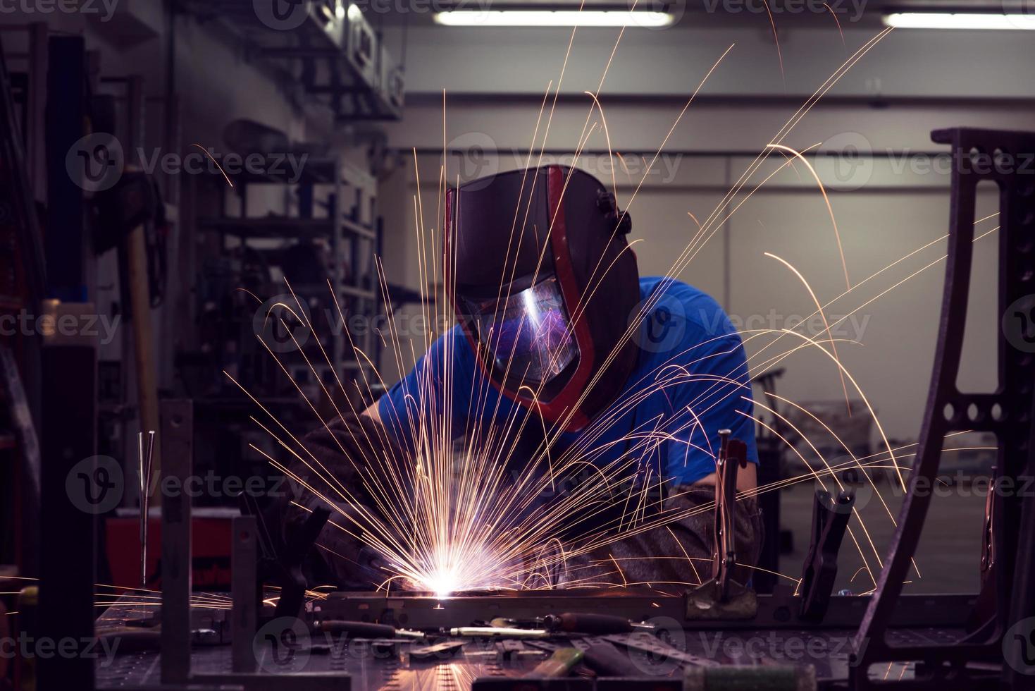 professioneller Schweißer aus der Schwerindustrie, der in der Fabrik arbeitet, einen Helm trägt und mit dem Schweißen beginnt. selektiver Fokus foto