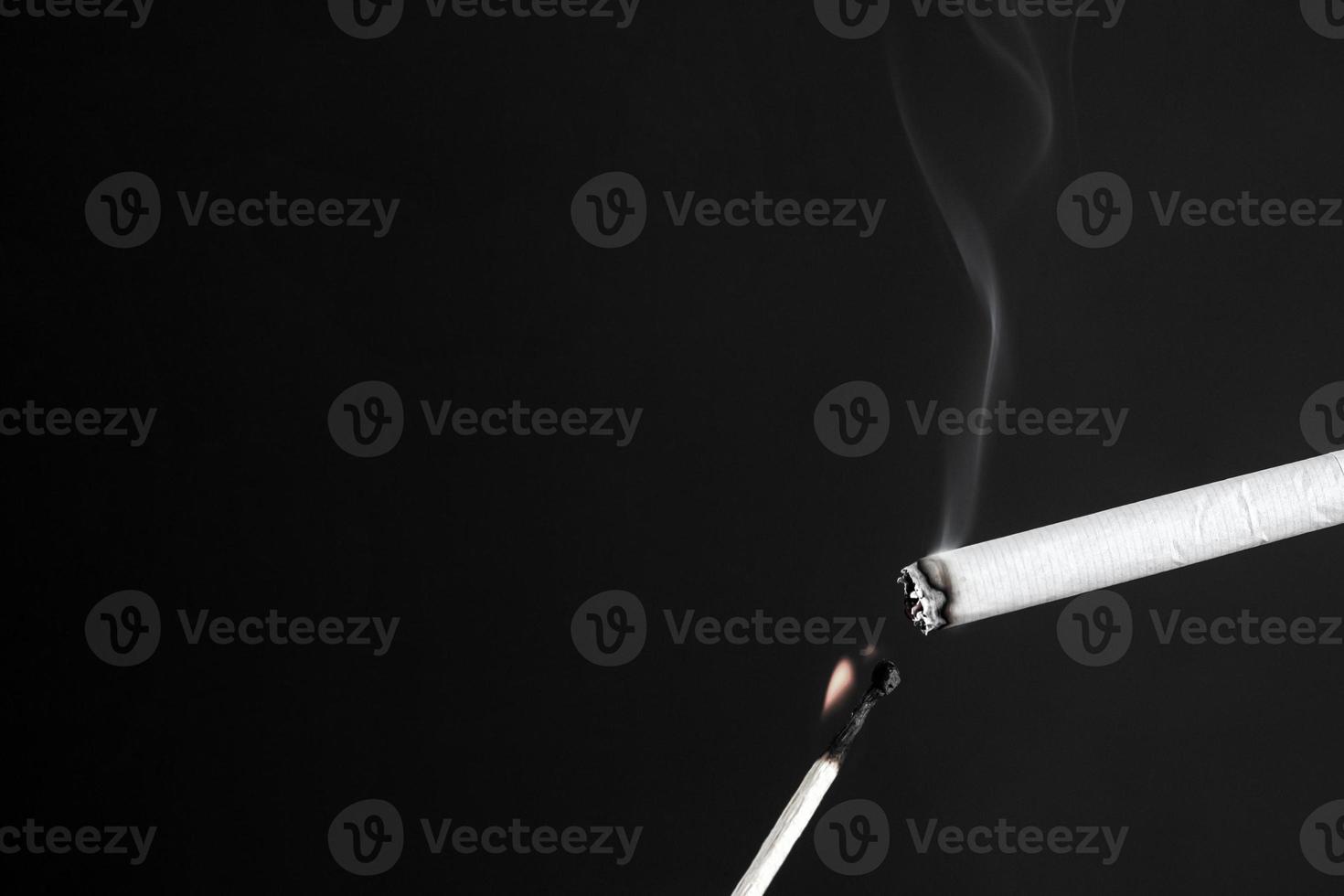 eine Zigarette mit einem brennenden Streichholz in schwarz und weiß anzünden foto