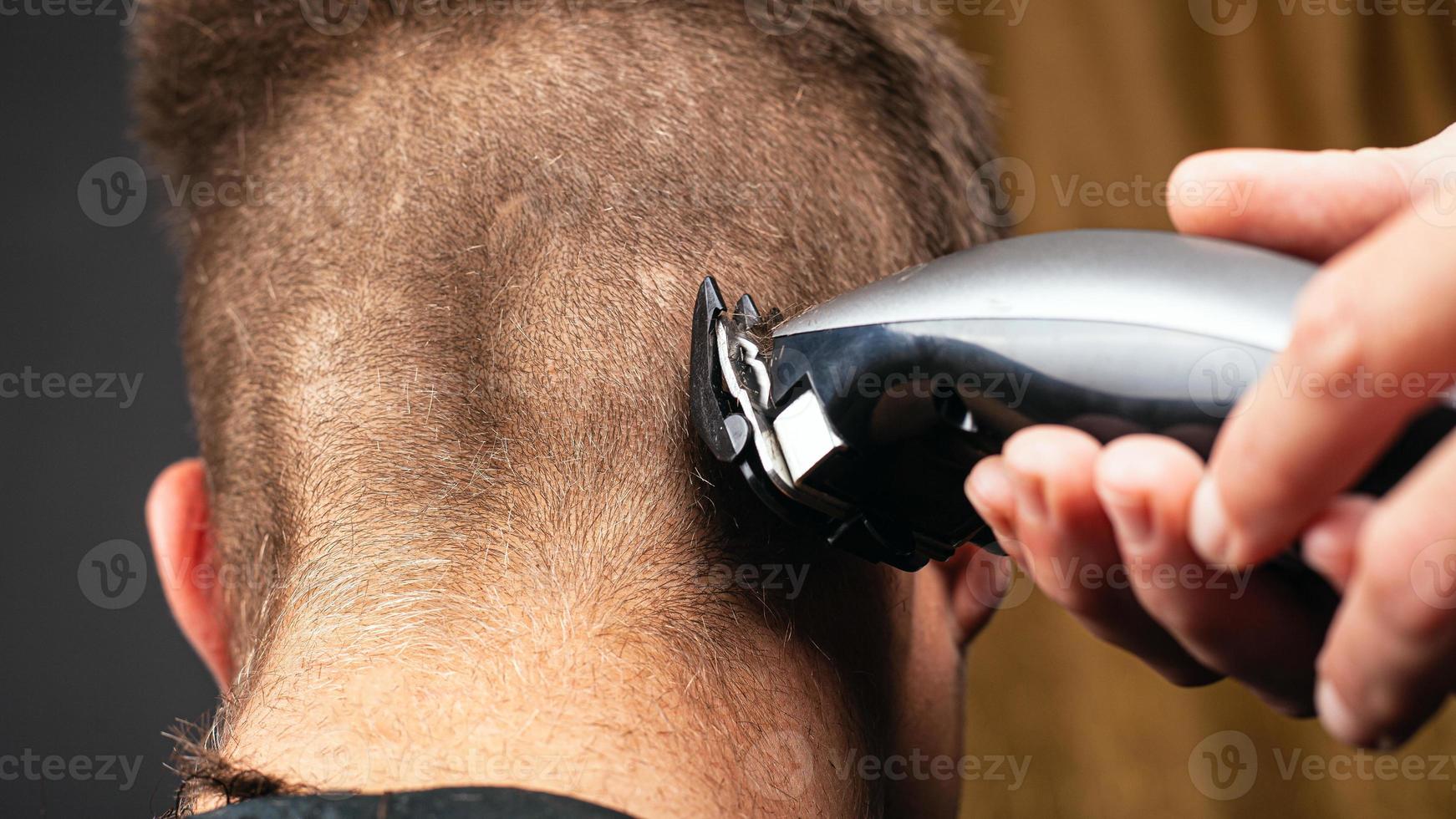 Haare schneiden mit Trimmer, Friseur rasiert Haare foto