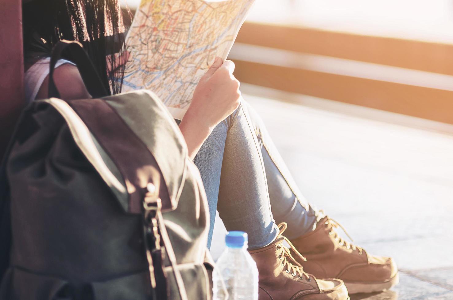 touristische reisefrau, die auf die karte schaut, während sie am bahnhof spazieren geht - straßenrucksack-reisekonzept foto