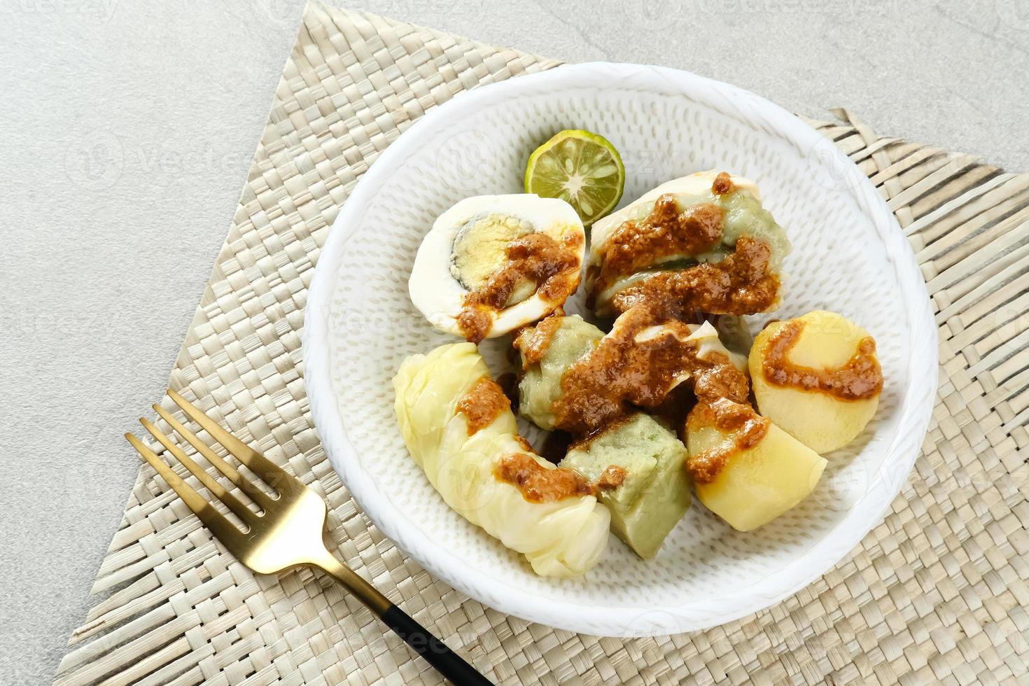 Siomay Bandung, gedämpfte Teigtaschen mit gekochtem Ei, Tofu, Kartoffeln und Kohlroulade. Traditionelles indonesisches Straßenessen mit Erdnusssauce und Sojasauce, serviert mit grüner Limette. foto