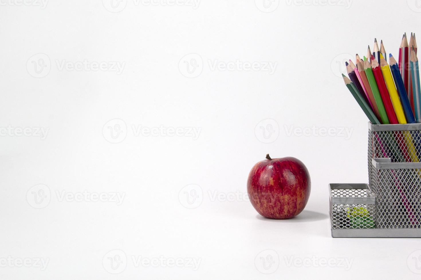 bildungselemente in der box, farbstifte, gesichtsmaske, büroklammern, schere, lineal, apfel isoliert auf weißem hintergrund. zurück zur Schule foto