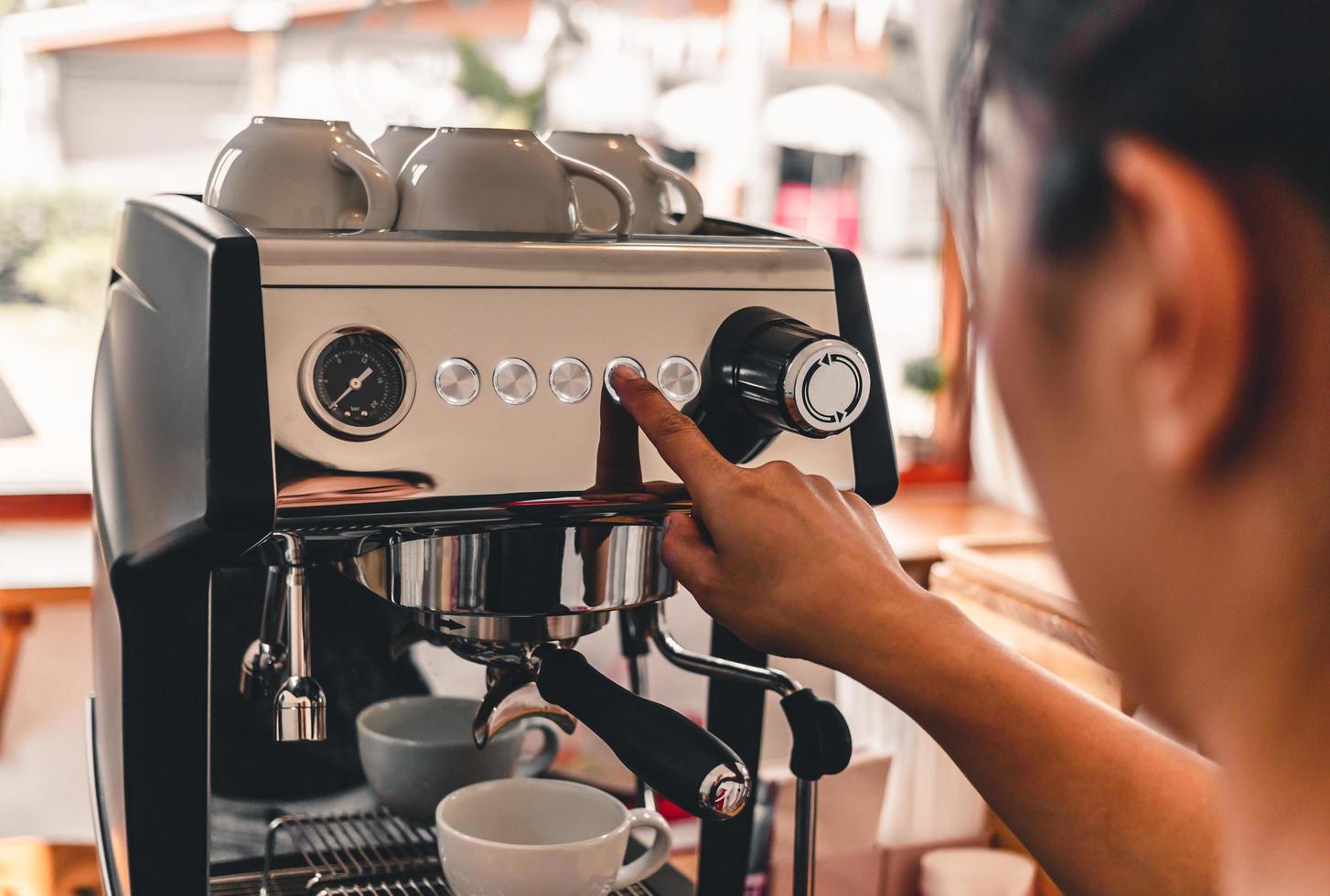 Nahaufnahme eines Baristas, der mit der Kaffeemaschine in einem Café Kaffee zubereitet foto