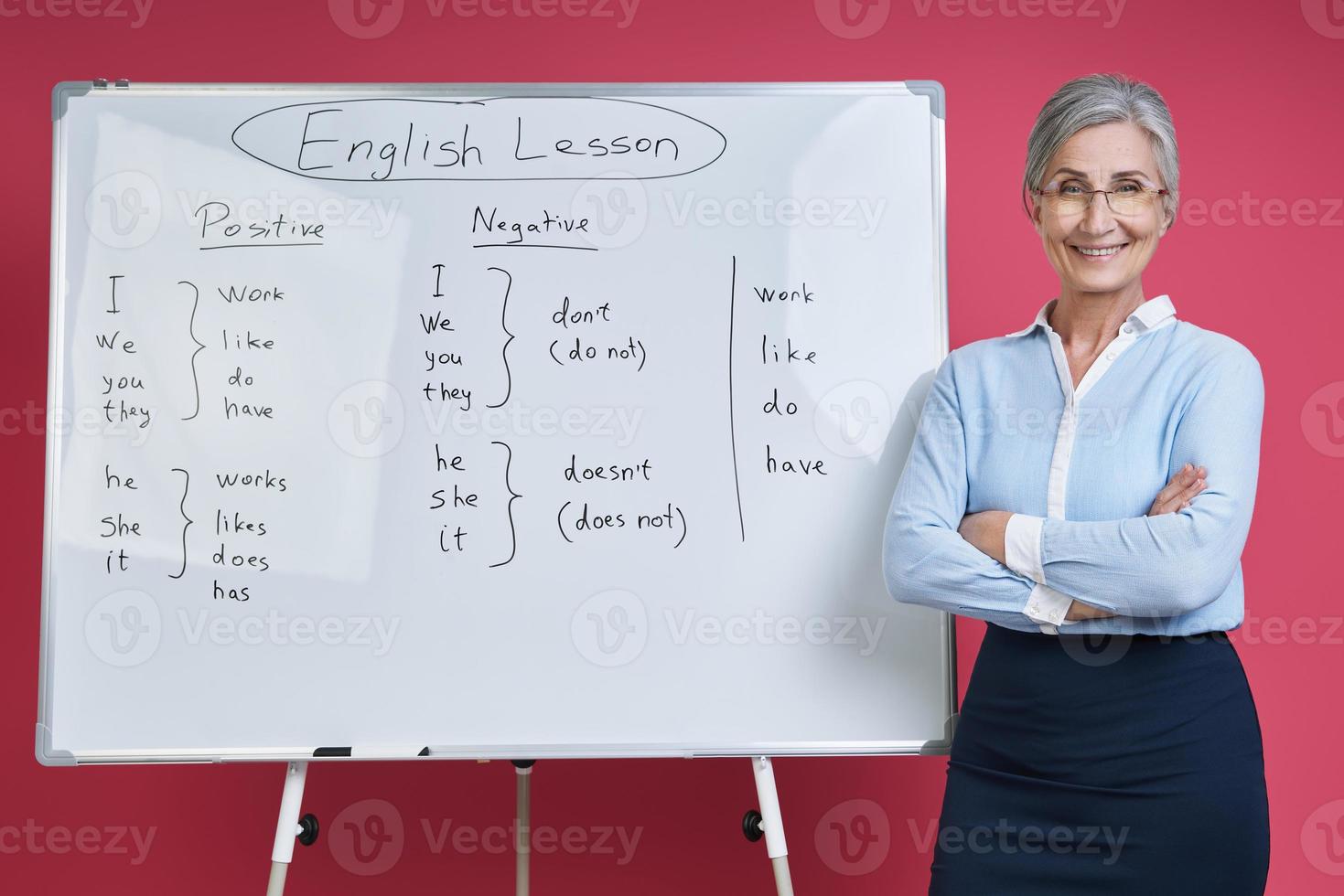 Seniorin unterrichtet Englisch in der Nähe des Whiteboards vor rosafarbenem Hintergrund foto