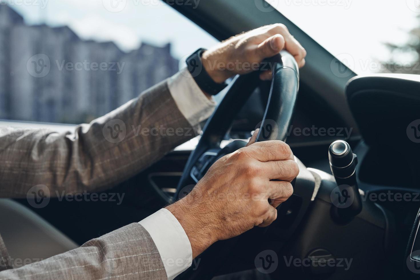 Nahaufnahme eines Mannes, der beim Autofahren die Hände am Lenkrad hält foto