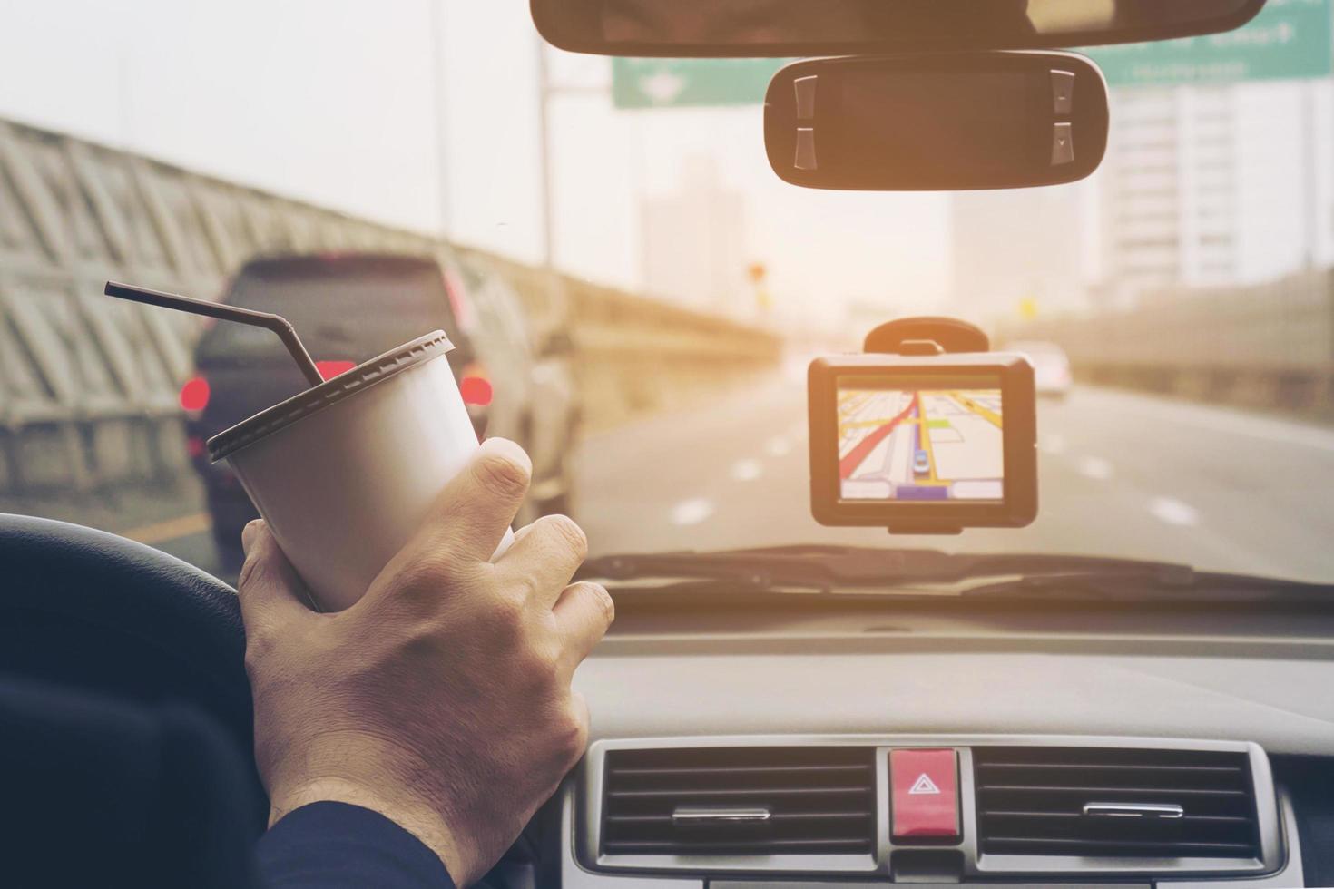 Mann, der Auto mit Navigator fährt und Kaffeetasse hält foto