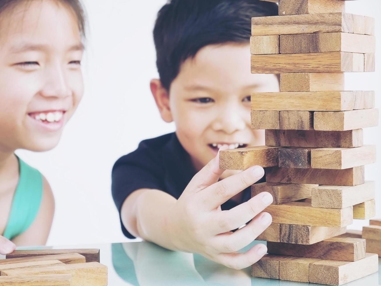 Kinder spielen ein Turmspiel aus Holzblöcken, um ihre körperlichen und geistigen Fähigkeiten zu üben foto