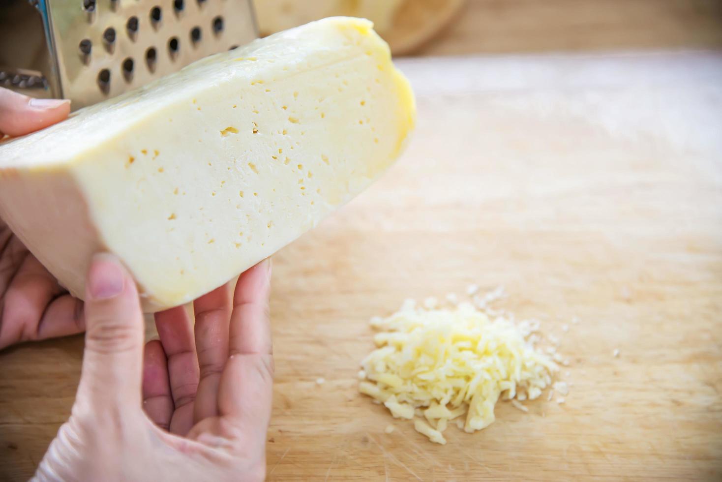 frau, die käse für koch mit käsereibe in der küche zubereitet - leute, die lebensmittel mit käsekonzept zubereiten foto