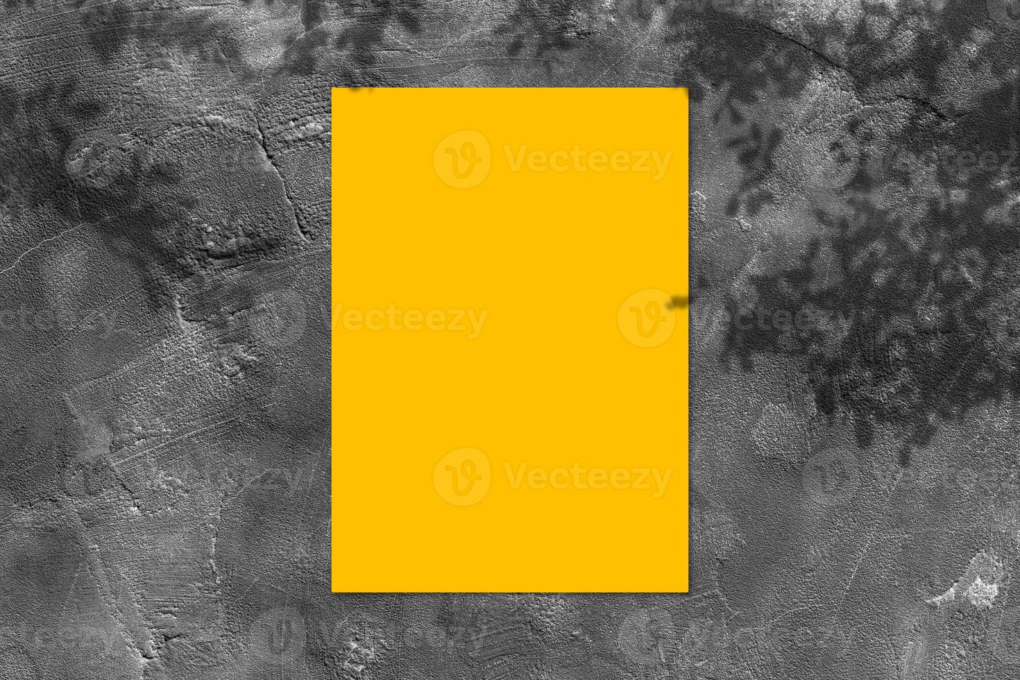 leeres gelbes quadratisches plakatmodell mit hellem schatten auf schwarzem betonwandhintergrund. foto