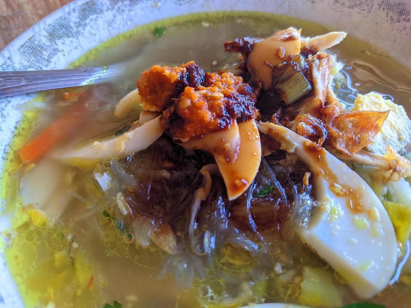 Nahaufnahme von Suppe mit Eierscheibe und Sauce oder Sambal auf Indonesisch foto