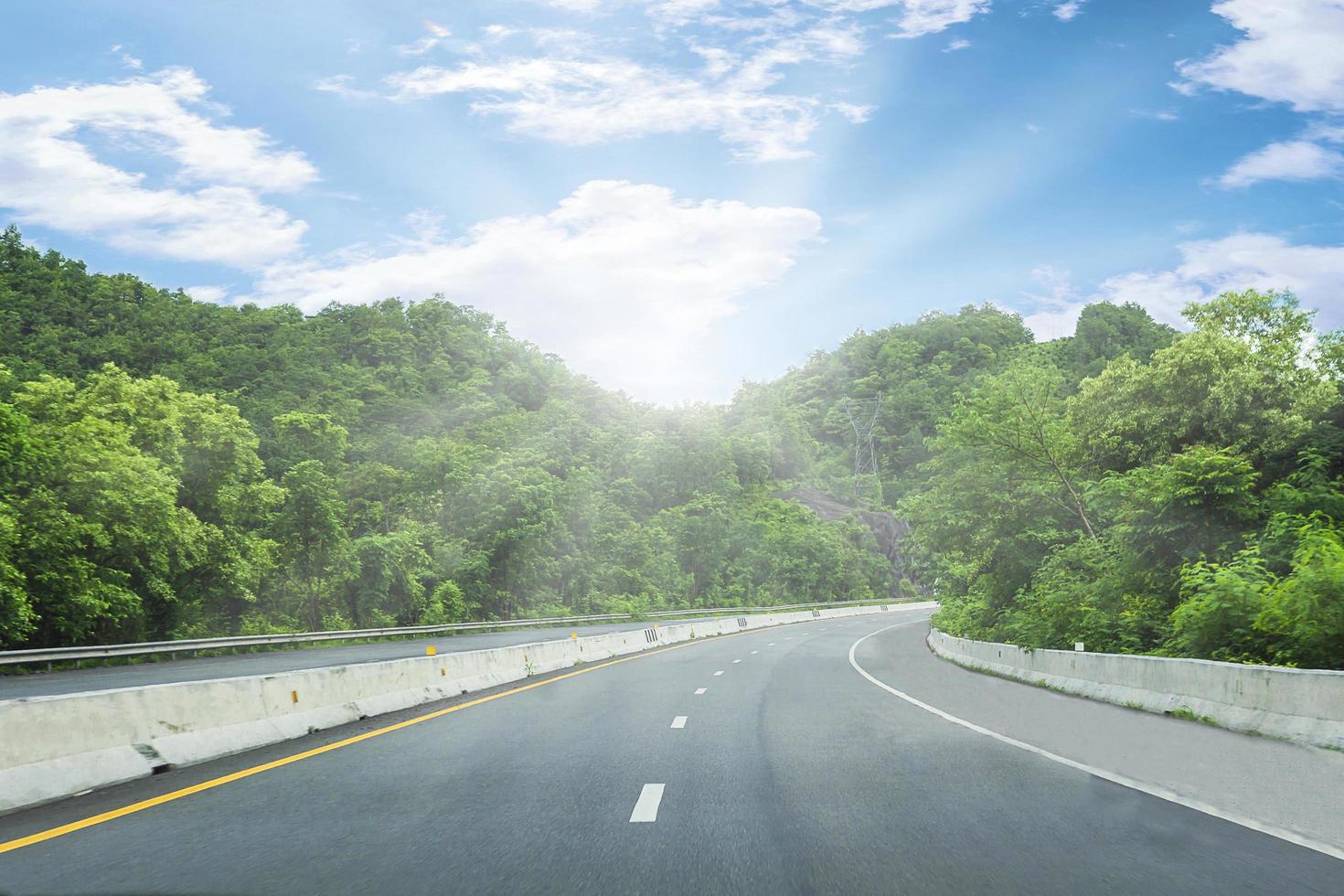 schöne autobahnstraße von thailand mit grünem berg und blauem himmelhintergrund foto