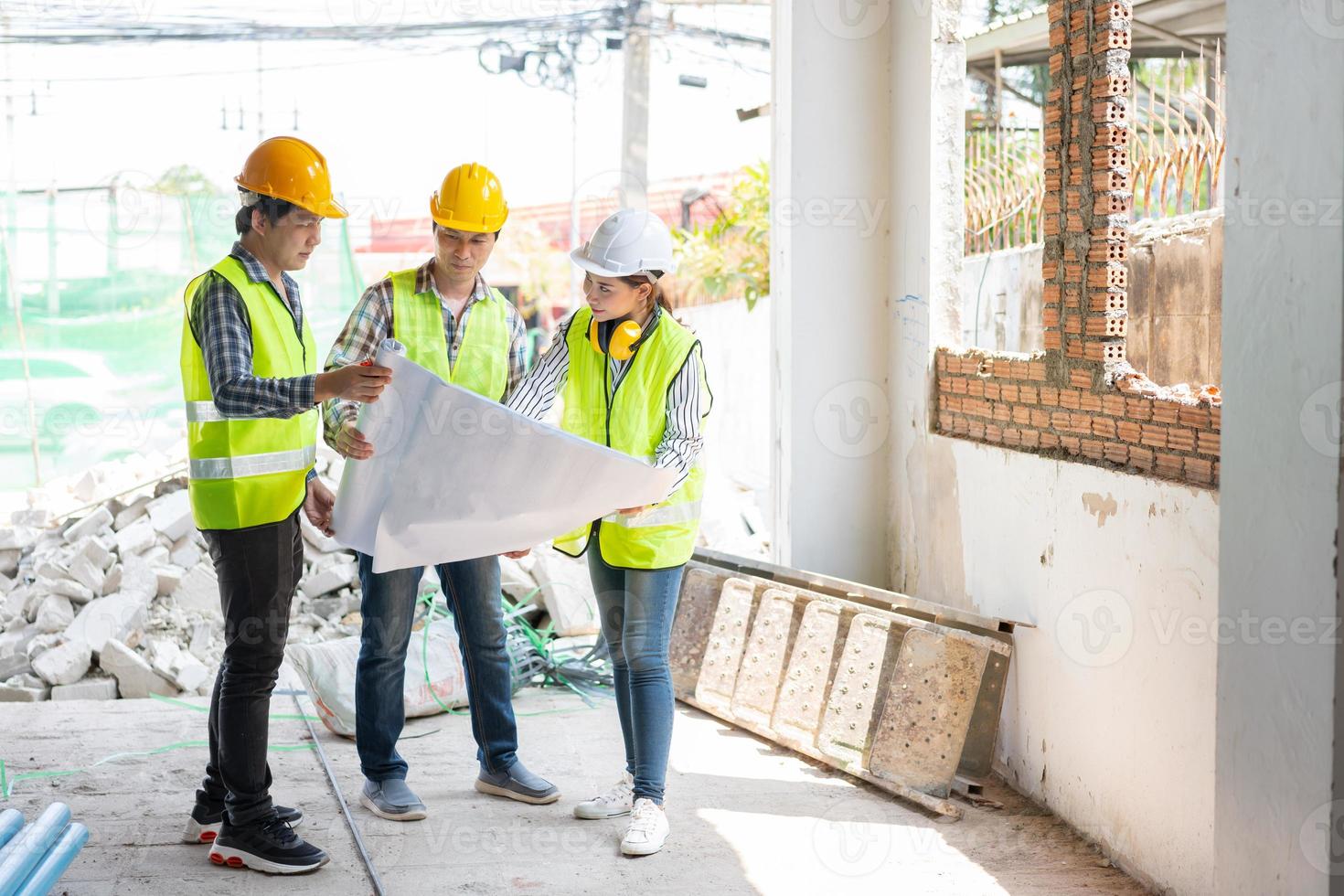 asiatische ingenieurin oder junge architektin setzen aus sicherheitsgründen einen helm auf und sprechen mit einem auftragnehmer über ein bauwerksprojekt, konzept der teamarbeit, führungskonzept. foto