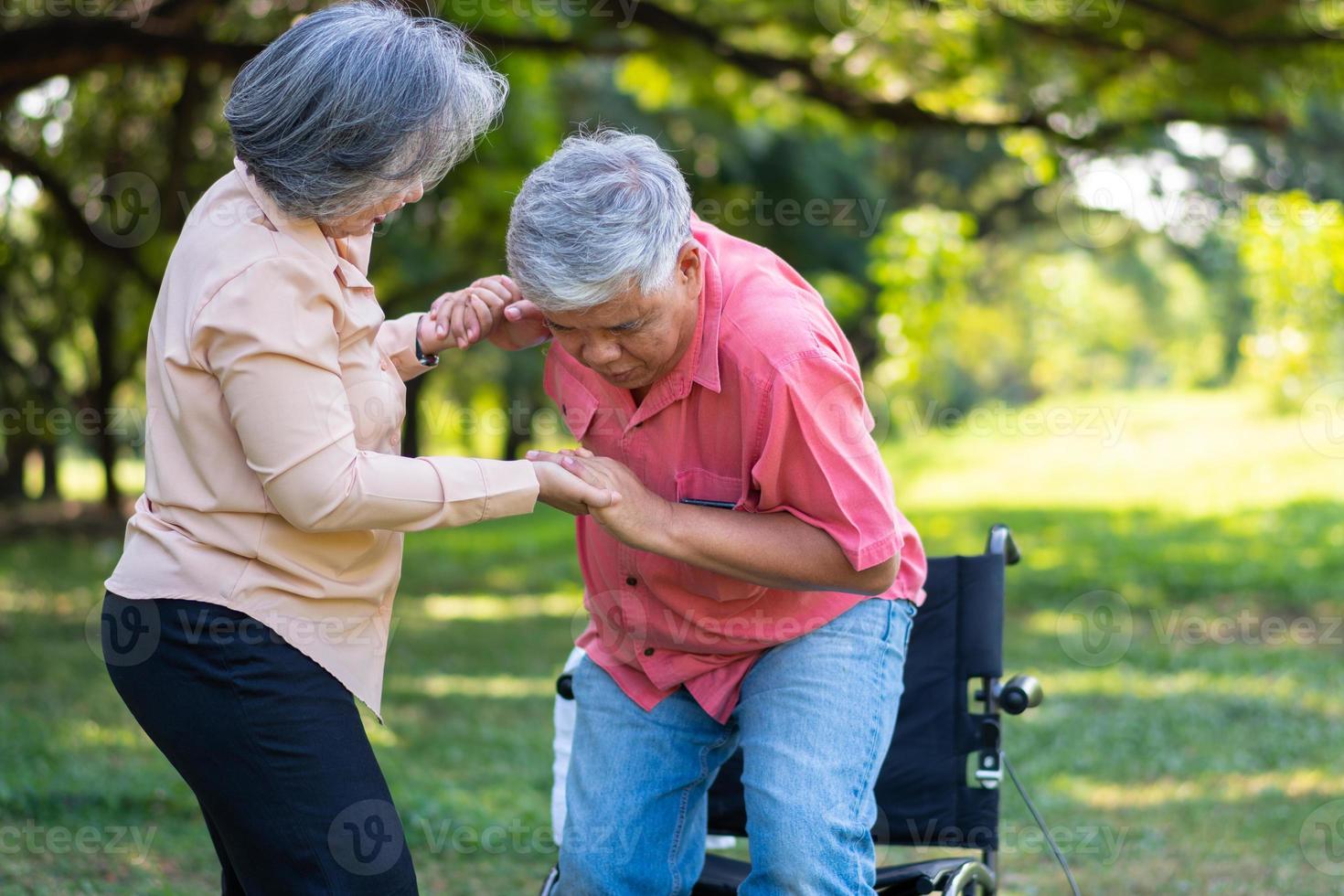 Ein asiatischer Senior fiel im Park auf den liegenden Boden, nachdem er gestolpert war und vor Schmerzen geweint hatte, und seine Frau kam, um zu helfen. konzept der alten versicherung und gesundheitsversorgung foto