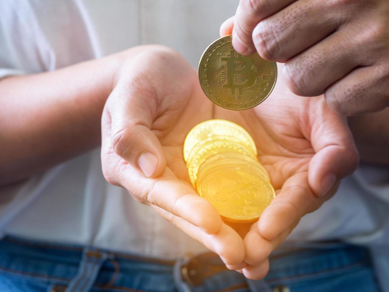 Nahaufnahme eines Mannes, der eine Bitcoin-Münze auf die Hände der Frau legt foto