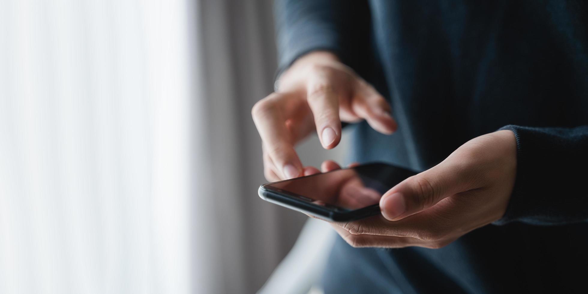 glücklicher asiatischer mann, der zu hause im wohnzimmer ein smartphone auf dem sofa verwendet und daten und soziale medien im internet durchsucht. foto