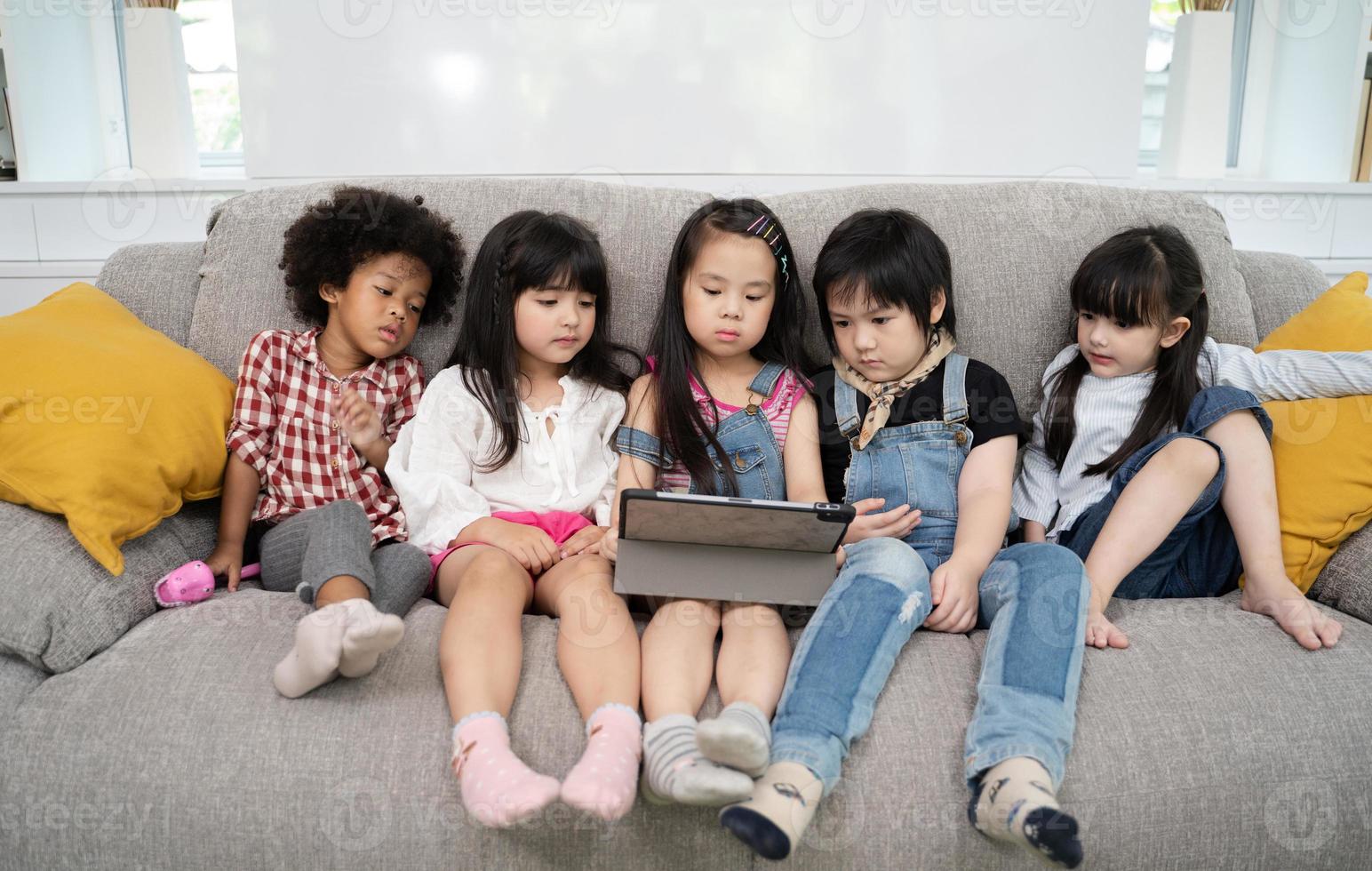 Gruppe kleiner Kinder, die gemeinsam Zeichentrickfilme auf einem digitalen Tablet ansehen foto