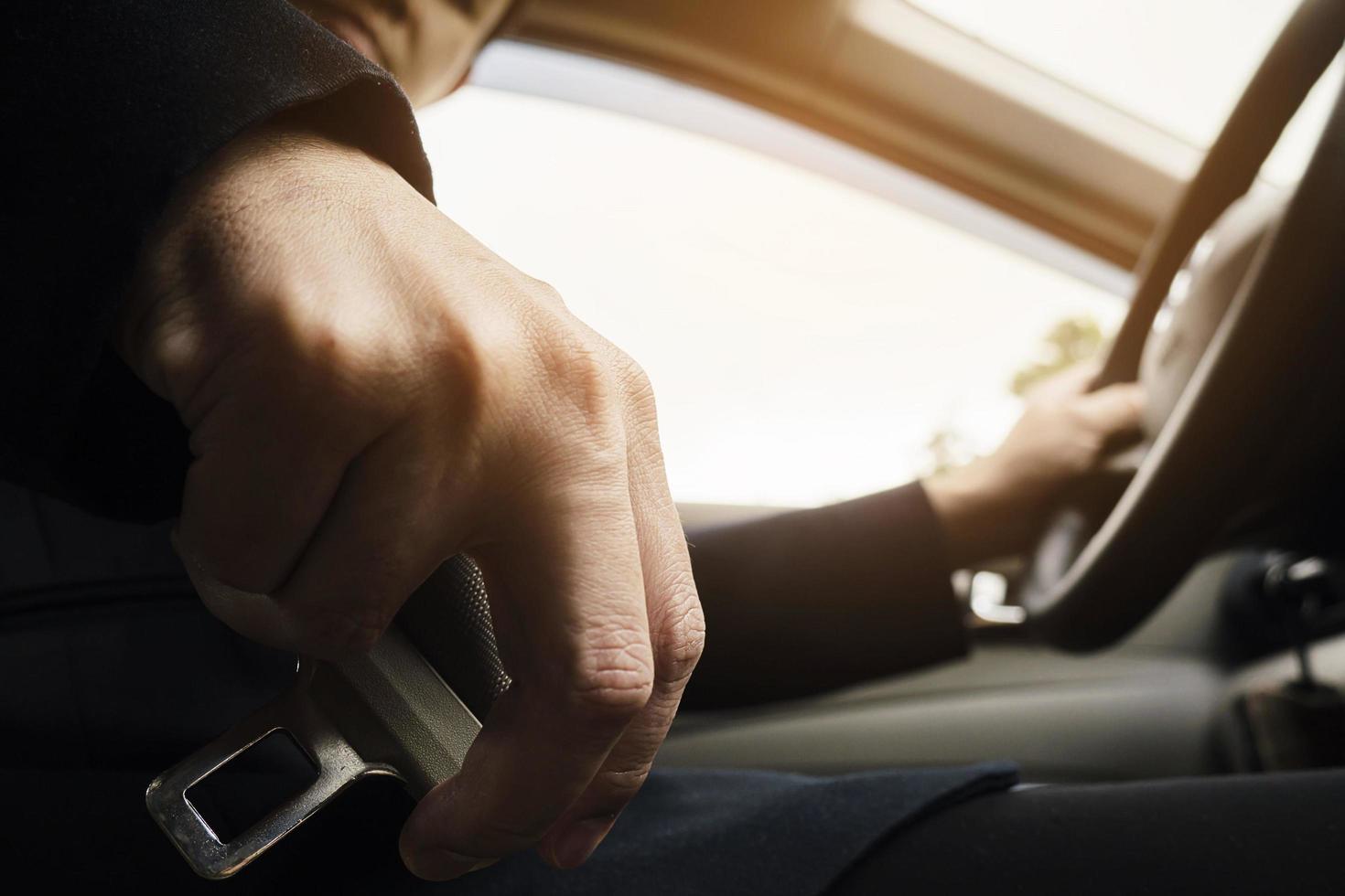 mann, der vor dem fahren den autosicherheitsgurt anlegt, nah an der gurtschnalle, sicheres fahrkonzept foto