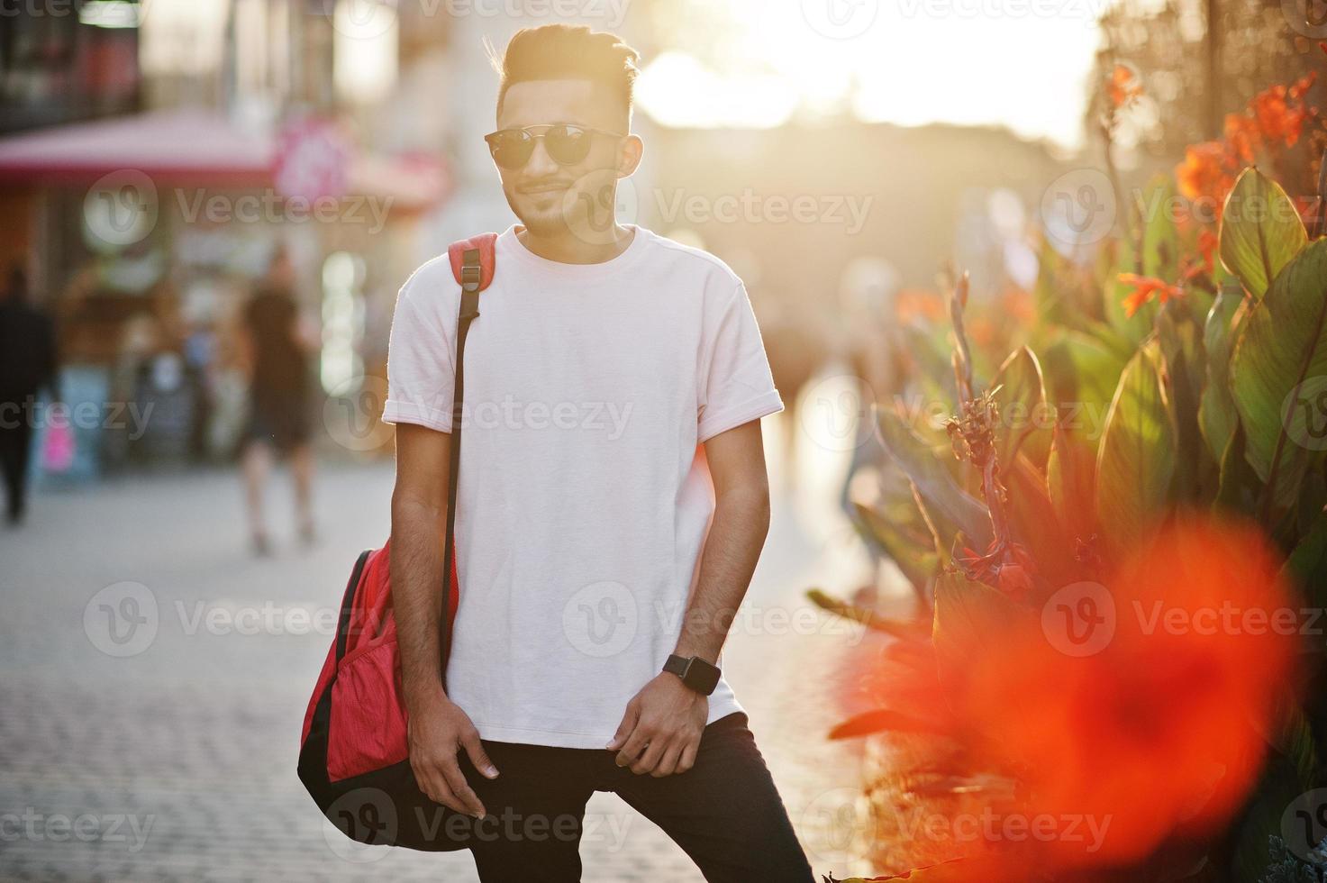 stilvoller indischer bartmann im rosa t-shirt, in der sonnenbrille und im rucksack. Indien-Model posierte im Freien auf den Straßen der Sonnenuntergangsstadt. foto