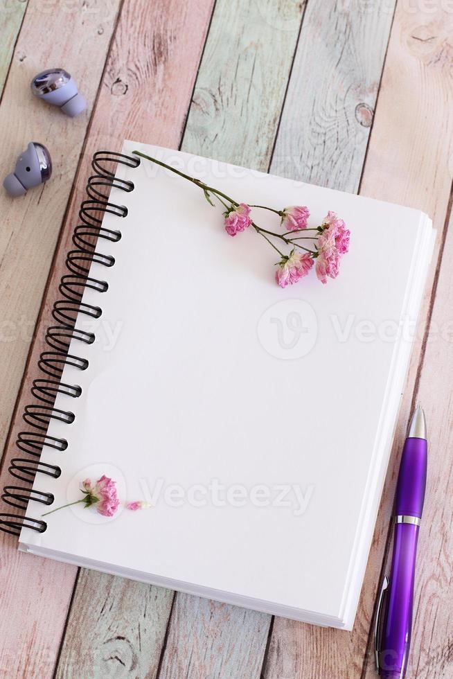 leere notizbuchseite mit blumen und stift auf holztisch foto