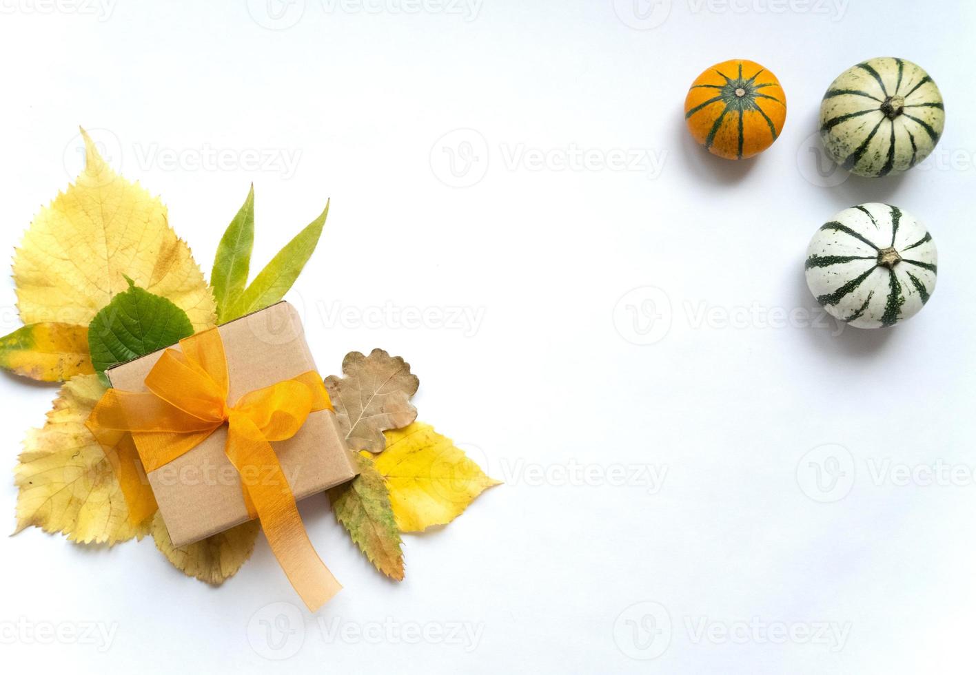 herbstblumenarrangement, komposition mit dekorativen kürbissen und herbstgelben blättern, geschenkbox mit orangefarbener transparenter bandvorlage für danksagung und herbstferien, konzeptionelle flache draufsicht foto