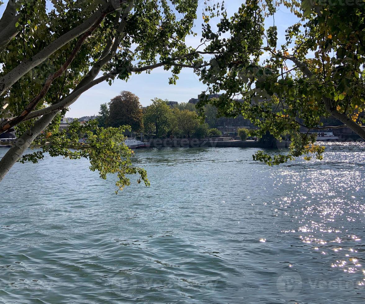 sommertag blick auf den fluss siene durch grüne bäume und blaue himmelsreflexion und glitzernde wasseroberfläche, typisches pariser stadtbild, wunderschönes panorama, stadt mit großer touristenattraktion foto