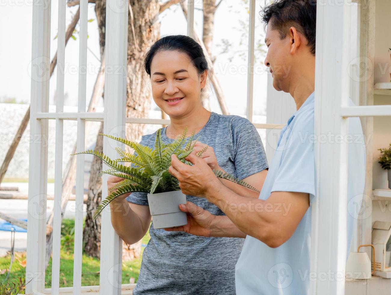 zwei Menschen mittleren Alters, die als Hobby pflanzen, Porträt. lächelnd paar person glücklich freizeit gartenarbeit im freien. reifer ehemann und ehefrau gartenbau haben einen sorglosen gesunden lebensstil, der pflanzen anbaut. foto