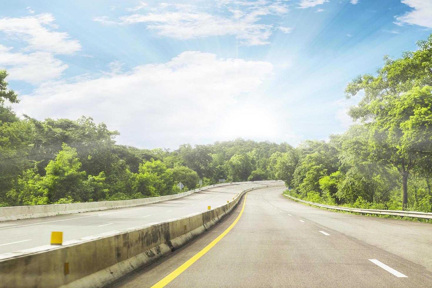 schöne autobahnstraße von thailand mit grünem berg und blauem himmelhintergrund foto