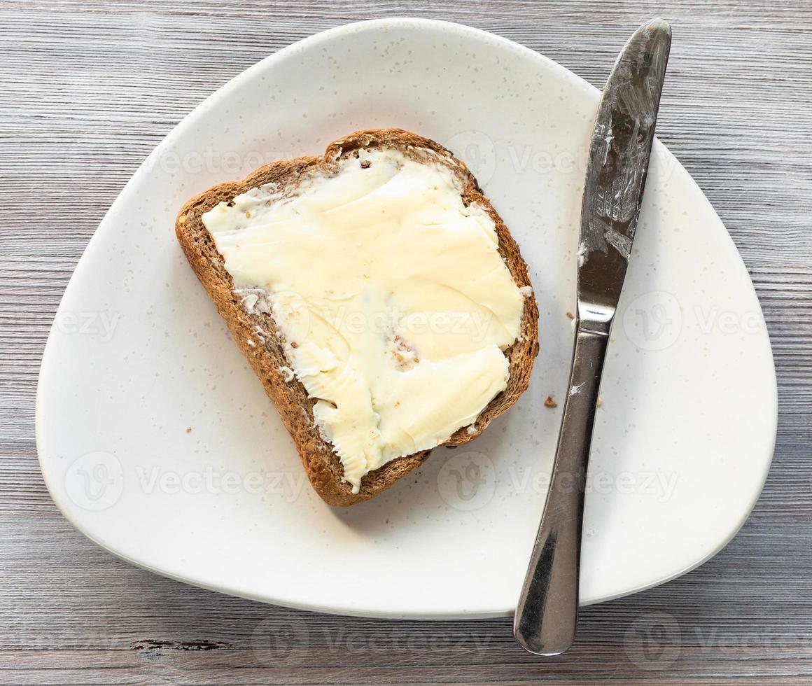 Sandwich mit Butter und Messer auf dem Teller auf dem Tisch foto