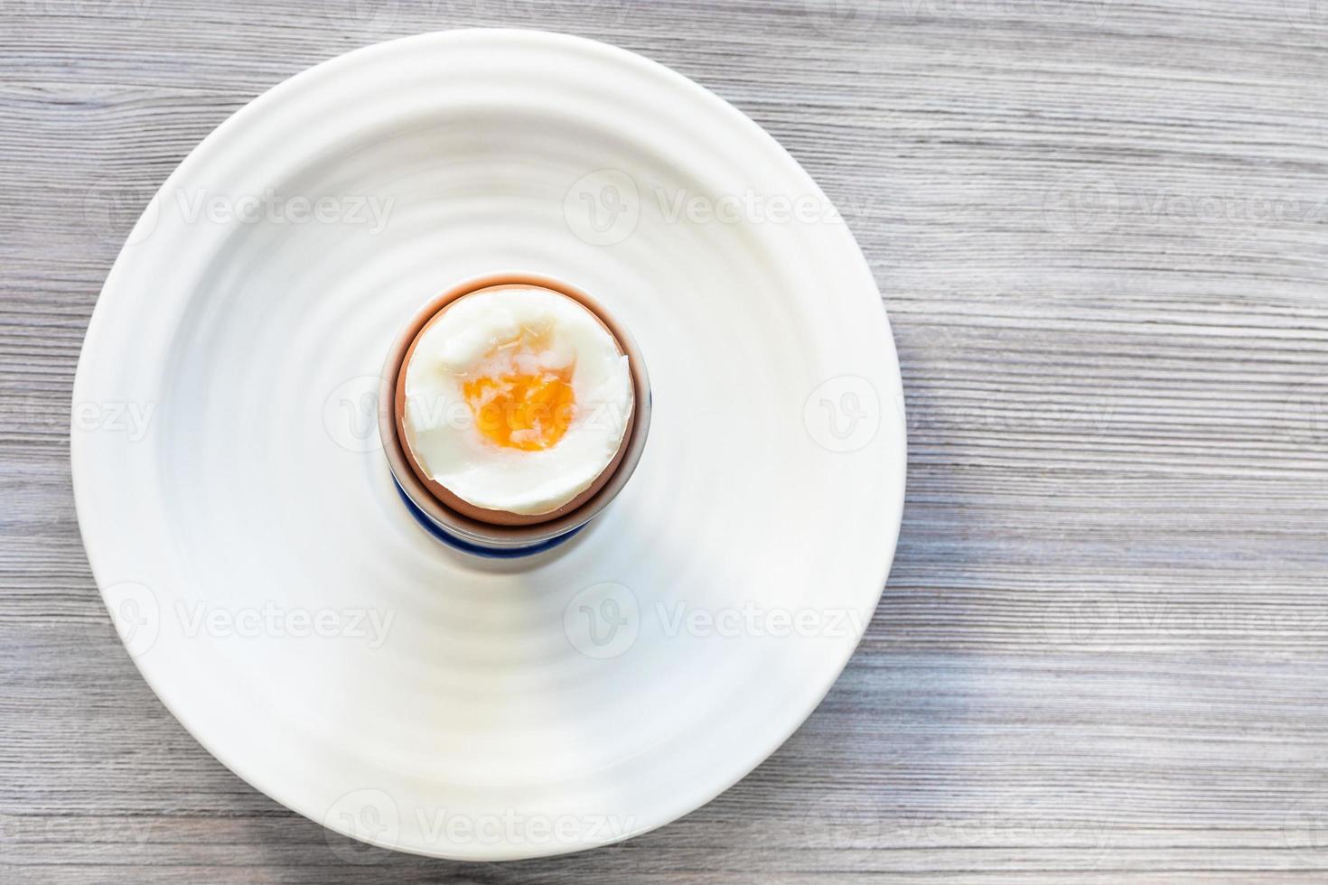 weich gekochtes braunes ei in der tasse auf dem teller auf grau foto