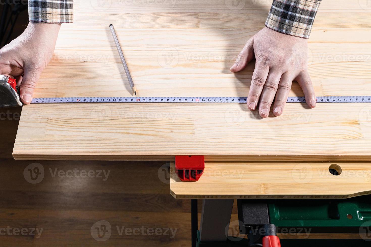 Hände des Zimmermanns messen die Größe auf einem Holzbrett foto
