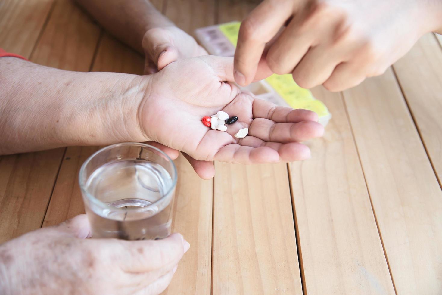 Der Arzt hilft dem Patienten, die Medizintablette in der Pillendose richtig zu essen - medizinisches Konzept der Menschen foto