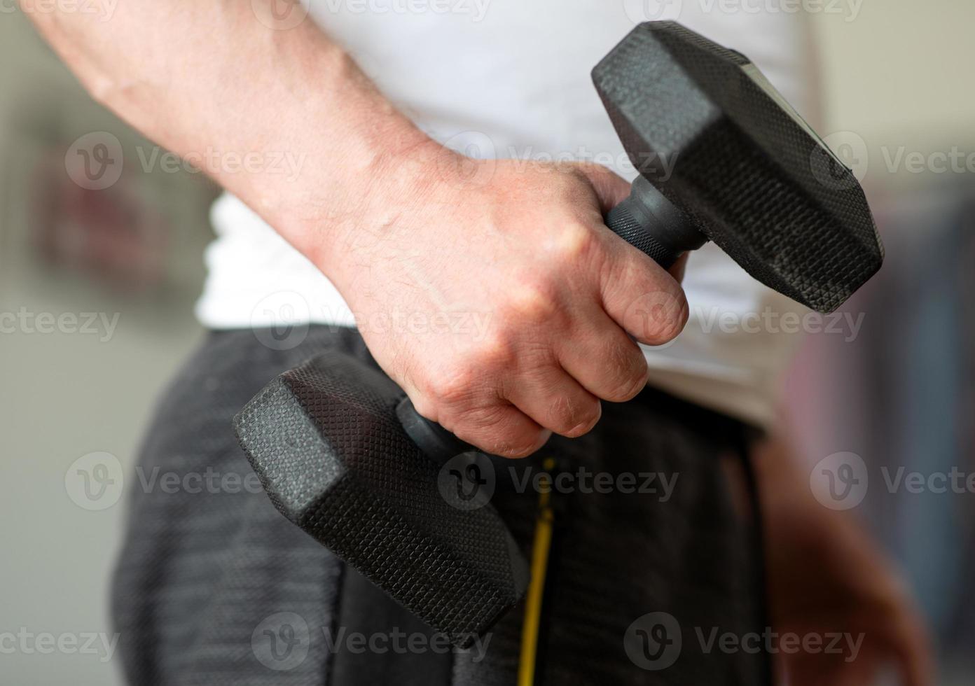 Training mit Hanteln zu Hause. der mann trainiert zu hause. Nahaufnahme einer männlichen Hand mit einer 5-kg-Hantel foto